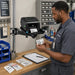 Facilities technician reviewing equipment identification labels printed from a TSC printer on an Agoz pole-mounted shelf.