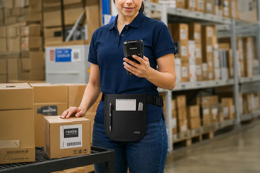 Almex mobile computer utility apron worn by warehouse worker with notepad, pen, and box cutter in front pockets.