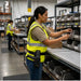 Worker wearing an Agoz waist belt scanner holster while organizing parts bins at a warehouse workstation.