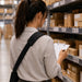 Warehouse worker reviewing inventory paperwork while wearing an Agoz shoulder sling case for hands-free mobile computer access during stock checks.