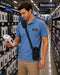 Man in a blue shirt with a Zebra Scanner case in a store aisle with electronics signage.