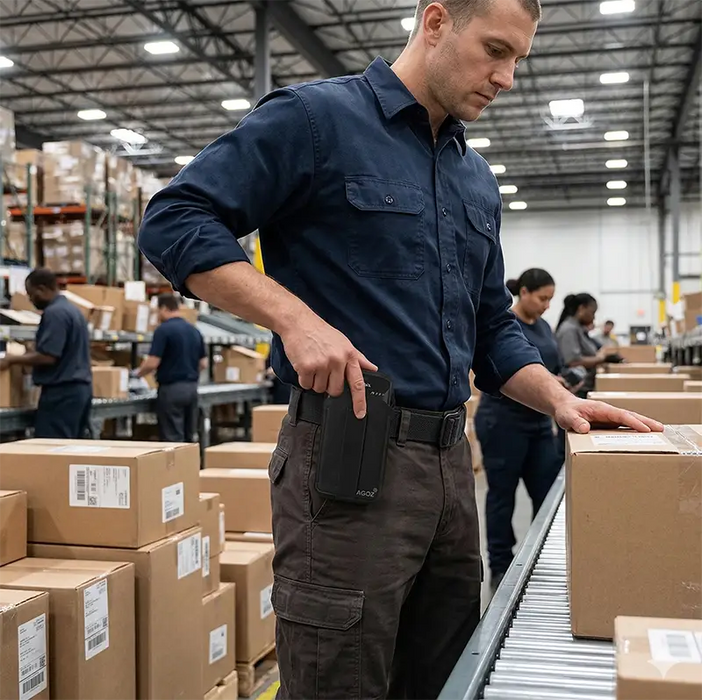 Warehouse worker using AgozTech black holster case with Zebra handheld mobile computer at packing station