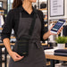 Retail employee holding a GoDaddy Smart Terminal Flex while wearing an Agoz crossbody holster for hands-free carrying.