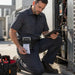 Field technician using Honeywell RP4f mobile printer carrying case with printed receipt while servicing HVAC equipment outdoors.