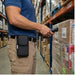 Warehouse worker wearing an AgozTech rugged CipherLab handheld case with belt clip while scanning pallet labels during inventory handling.