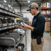 Worker using a Panasonic Toughbook handheld while wearing an Agoz case with card slot during inventory and field service workflow checks.