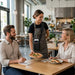 Restaurant server carrying a SpotOn payment terminal in an Agoz crossbody case while delivering a meal to seated guests.