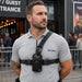Security worker wearing chest harness pouch for L3Harris two-way radio outside a venue