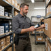 Warehouse worker using a Point Mobile scanner with belt case while checking inventory in a stockroom